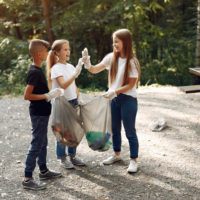 Volunteers collects rubbish. Children in a park. Kids in a white t-shirts